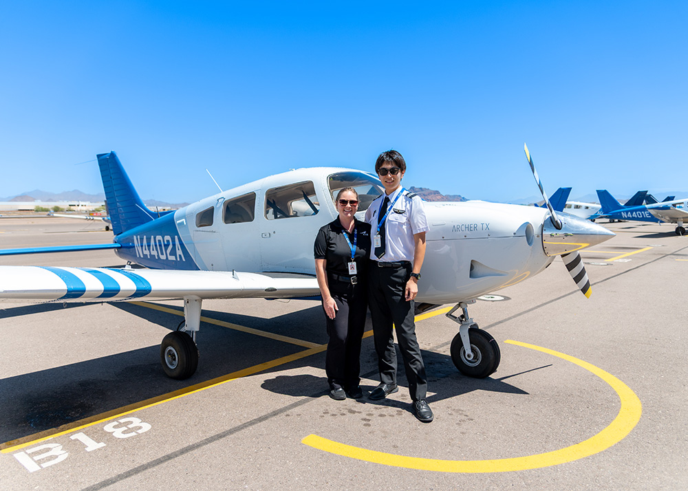 駐機中のArcher TX訓練機（N4402A）の前で記念撮影をする女性インストラクターと日本人パイロット訓練生の画像