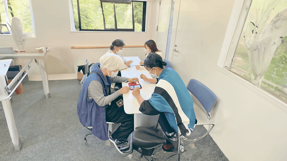 高齢者と学生がスマホを操作している様子