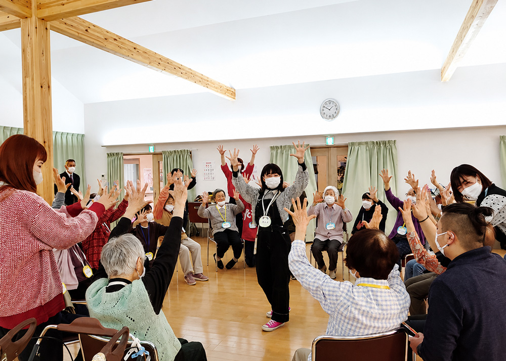 学生が高齢者施設で地域の人とダンスを踊っている様子