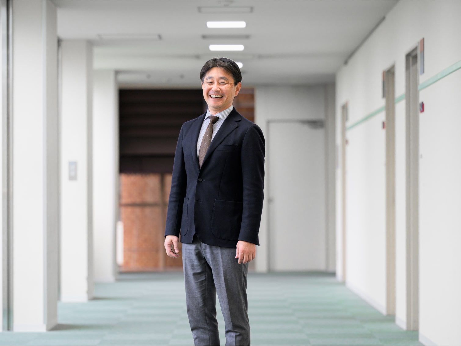 キャンパス内の廊下で笑顔を見せる多々良直弘先生