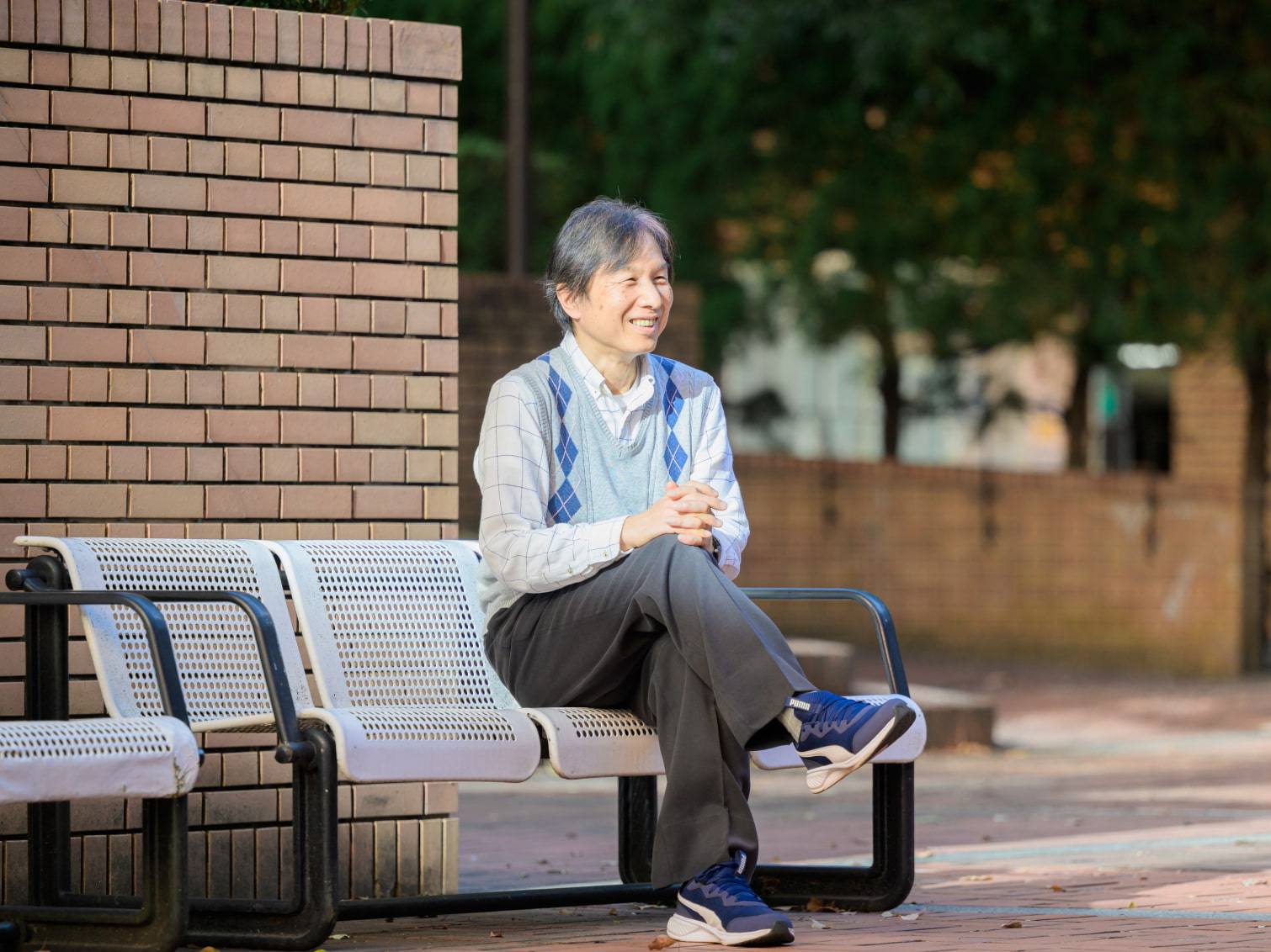 キャンパス内で笑顔で腰掛ける長谷川淳一先生