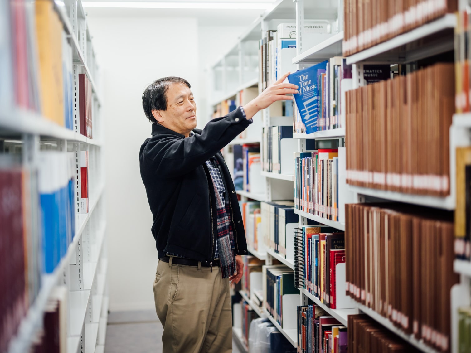 図書館で本を手に取る高岡明先生